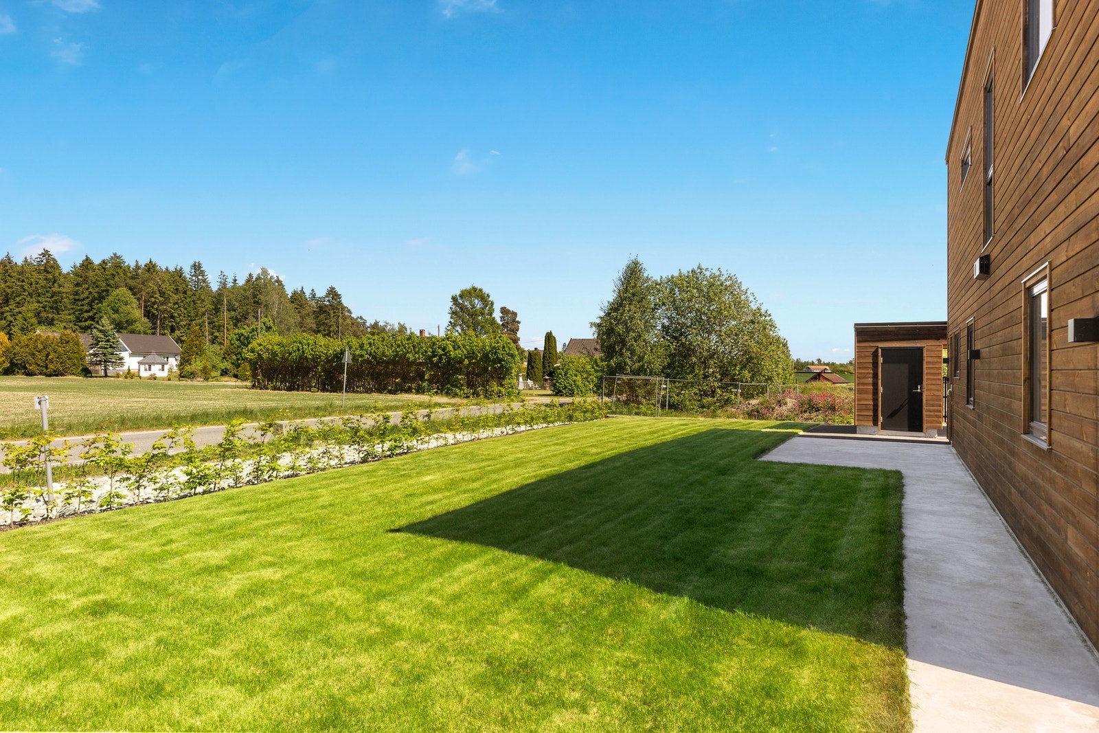 Eiendommen har ryddige uteområder med gressplen og bøkehekk. Lettstelt og pent. Galleribilde