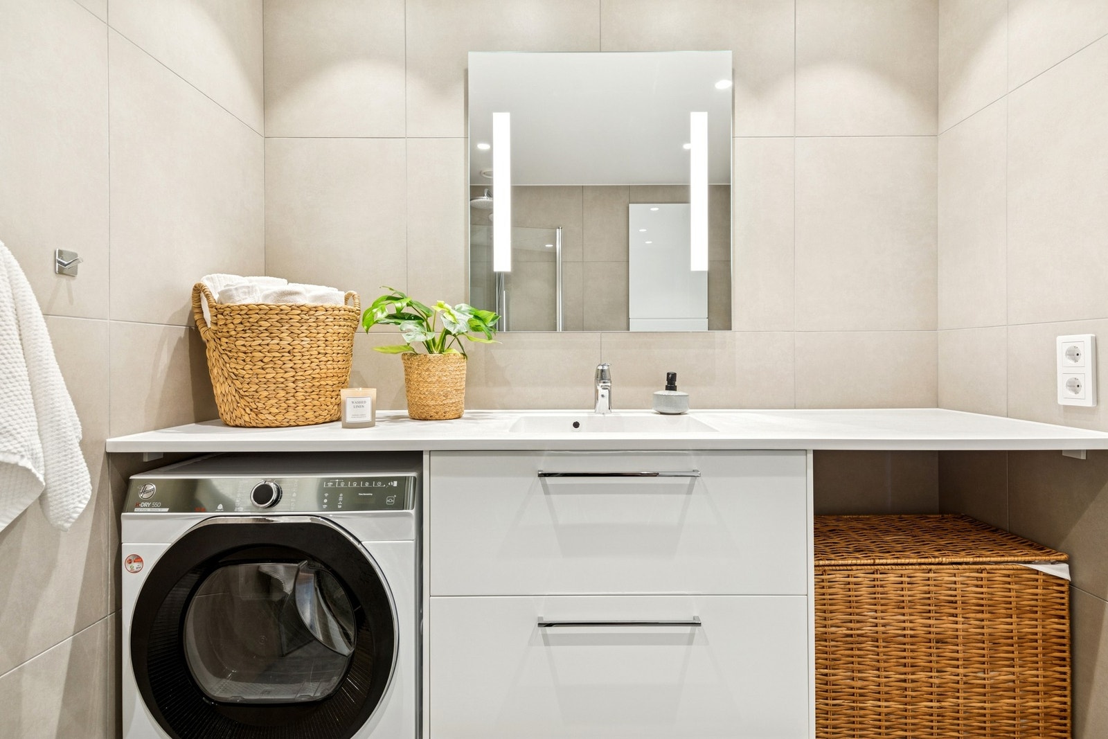 Baderommet har vegghengt servantinnredning med benkeplate og opplegg for vaskemaskin. Galleribilde