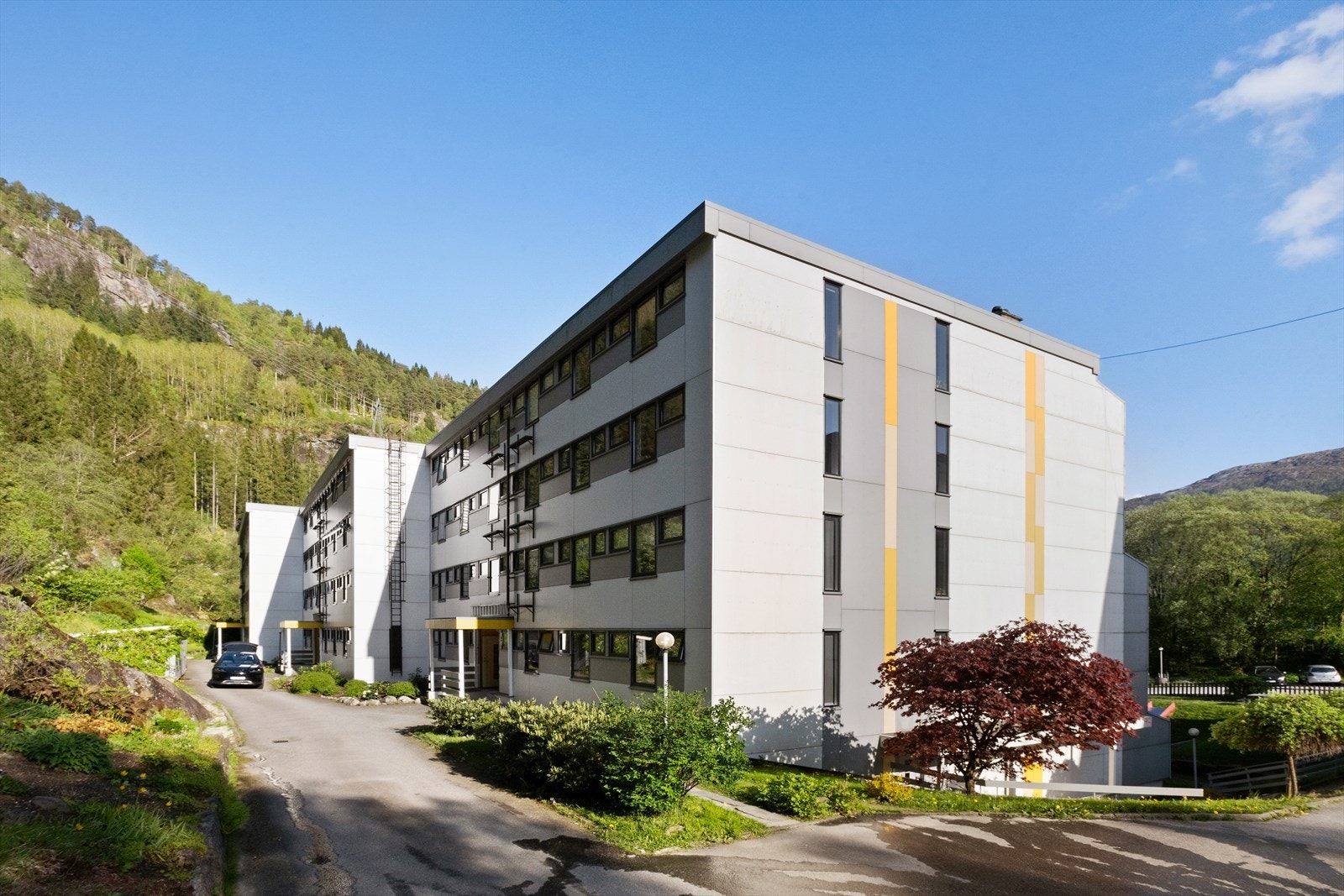 Blokken har inngang på baksiden. På enden av blokken er det dør til parkeringskjelleren hvor leiligheten disponerer en plass. Galleribilde