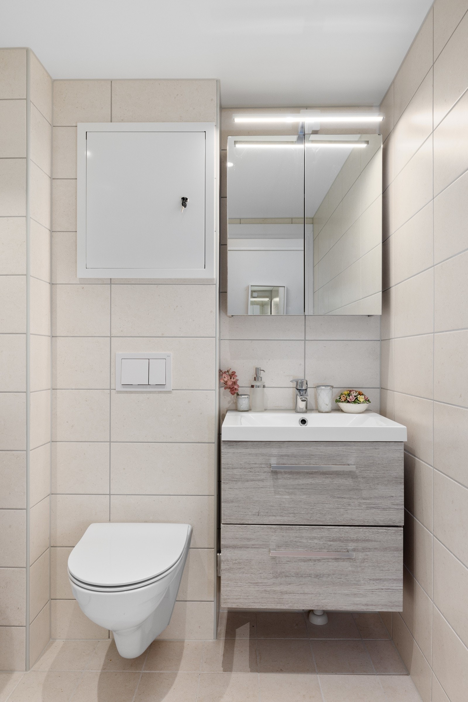 Badet er utstyrt med en nedfelt servant, veggmontert toalett, dusjkabinett og tilkobling for vaskemaskin. Galleribilde