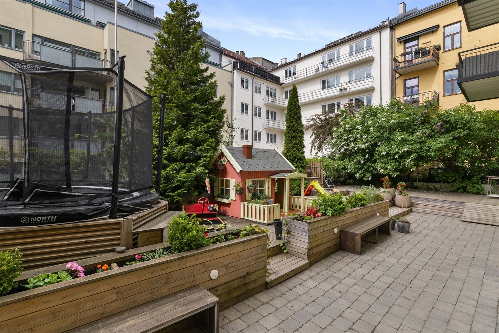 Flott opparbeidet bakgård med sittegrupper, lekeplass og beplantning. Galleribilde