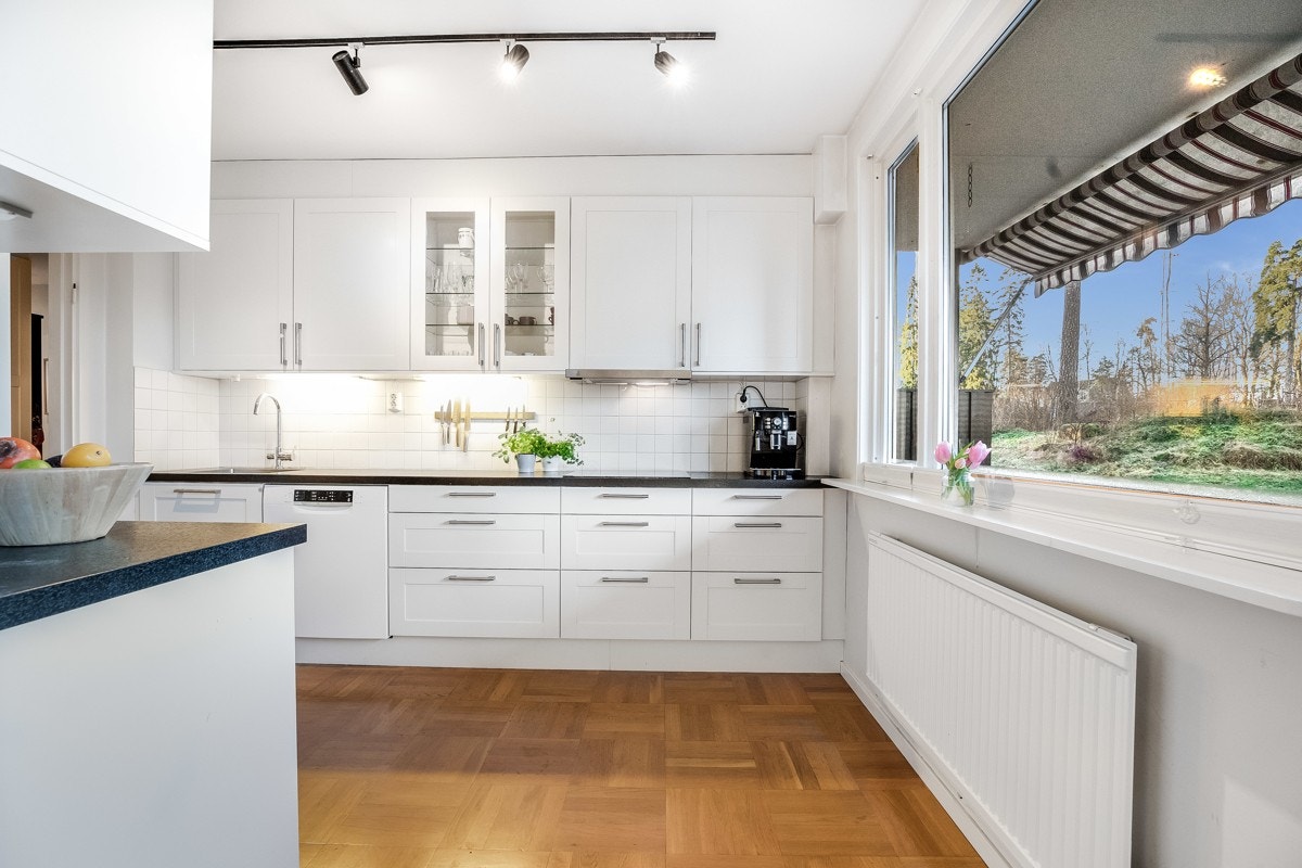 Stilrent kjøkken med hvit kjøkkeninnredning, profilerte fronter og laminat benkeplate Galleribilde