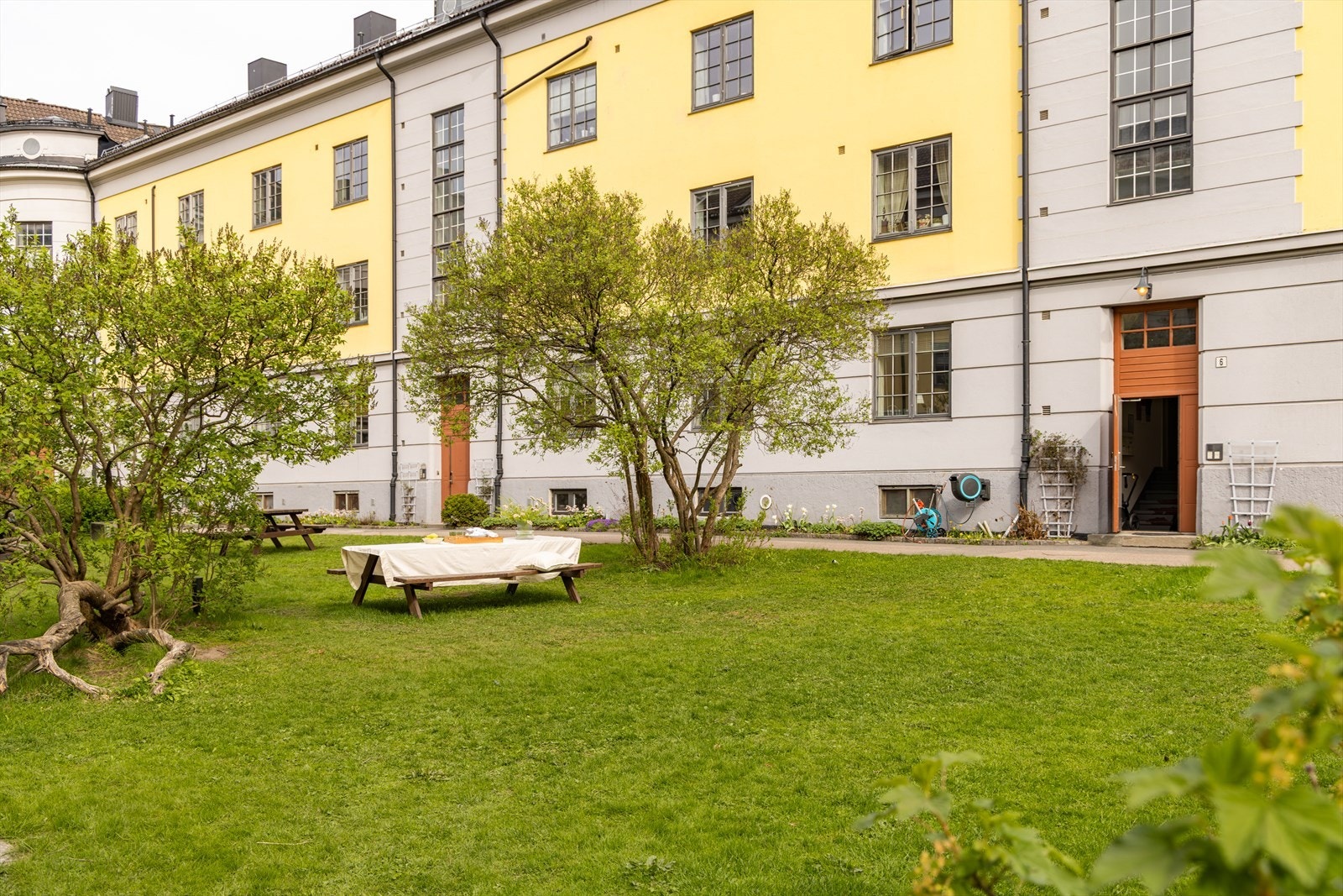 Pen lukket bakgård, med lekeplass, bærbusker, flere sittegrupper og felles griller. Galleribilde