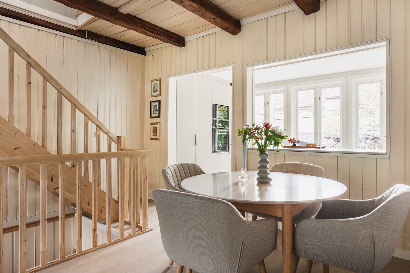 Spisestuen får rikelig med naturlig lys fra store vindusflater, og de synlige bjelkene og lyse treoverflatene gir rommet en varm og rustikk karakter. Her inviteres det til hyggelige måltider og gode samtaler rundt bordet. Galleribilde