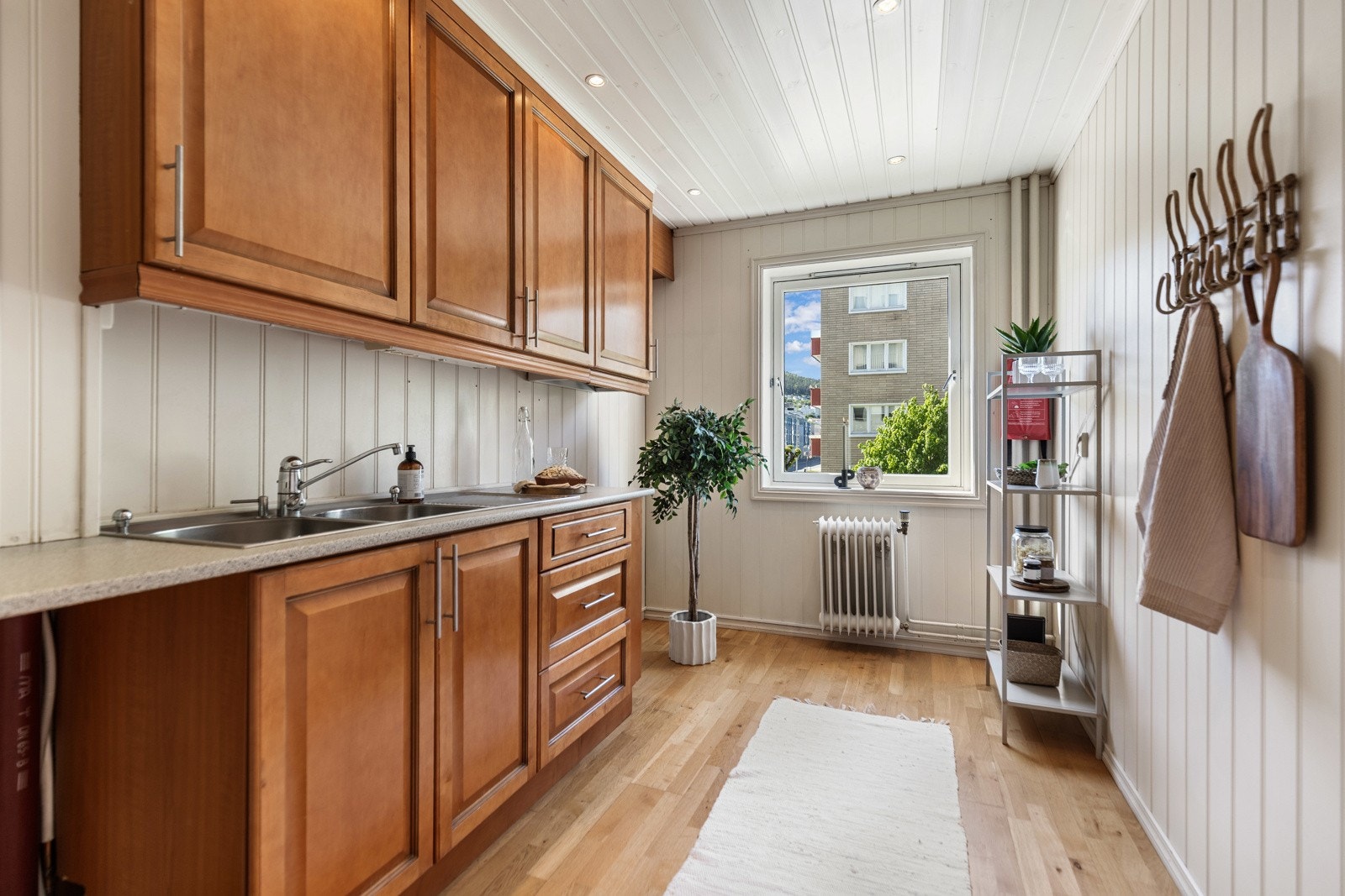 Kjøkkenet har lyse vegger, parkettgulv og store skap med god oppbevaringsplass. Vinduet gir naturlig lysinnslipp. Galleribilde