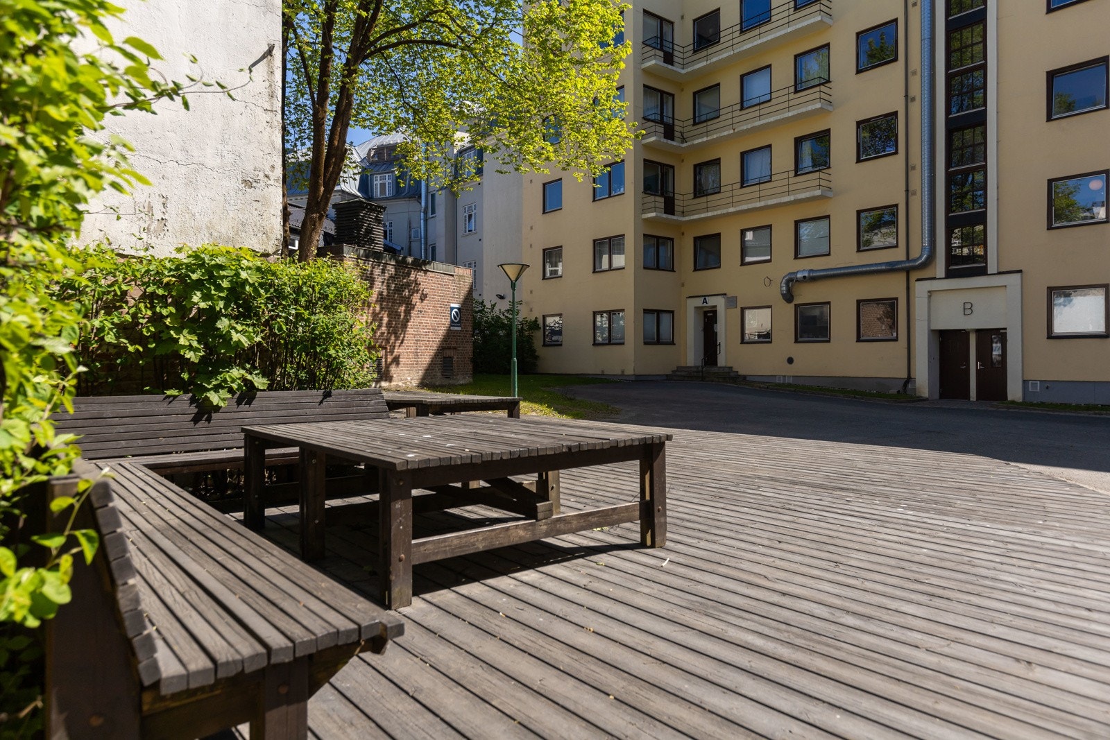 Felles uteområde med sittegruppe og tredekke, omgitt av grøntområder. Galleribilde