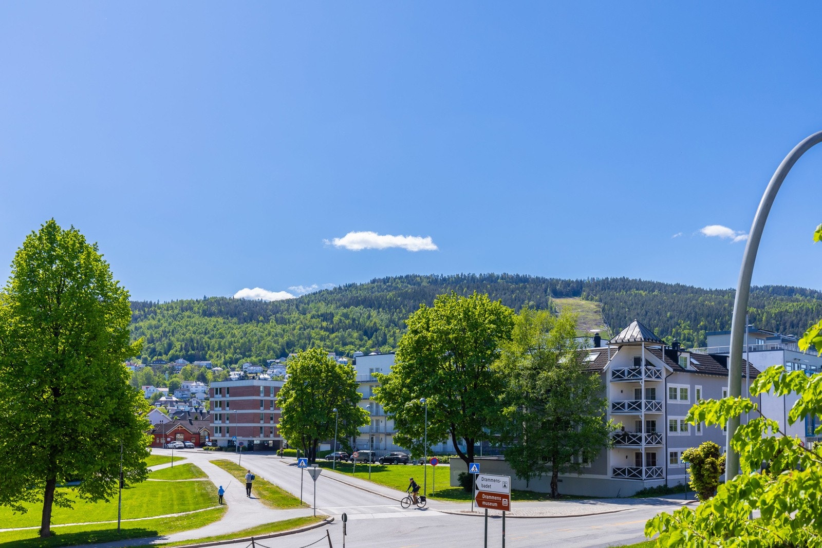 Utsikt mot grøntområde, boligblokker og skogkledde åser Galleribilde