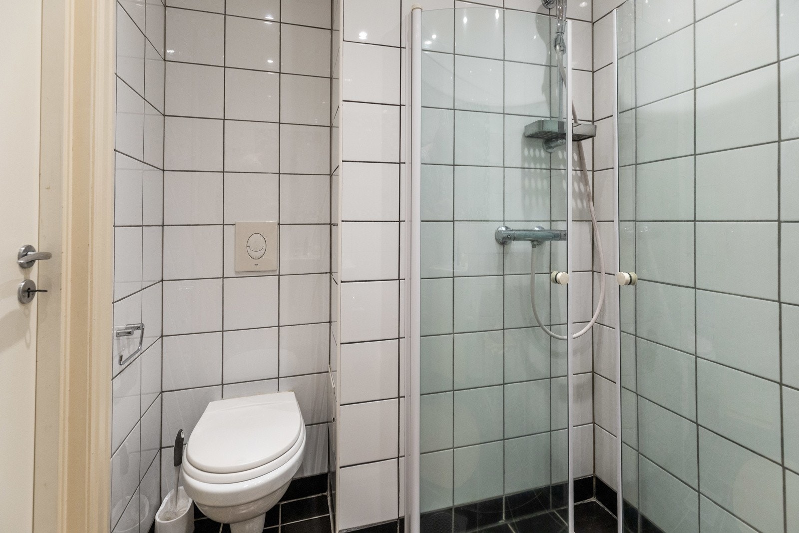 Badet har flislagte vegger og gulv, dusj med glassdører og vegghengt toalett. Galleribilde