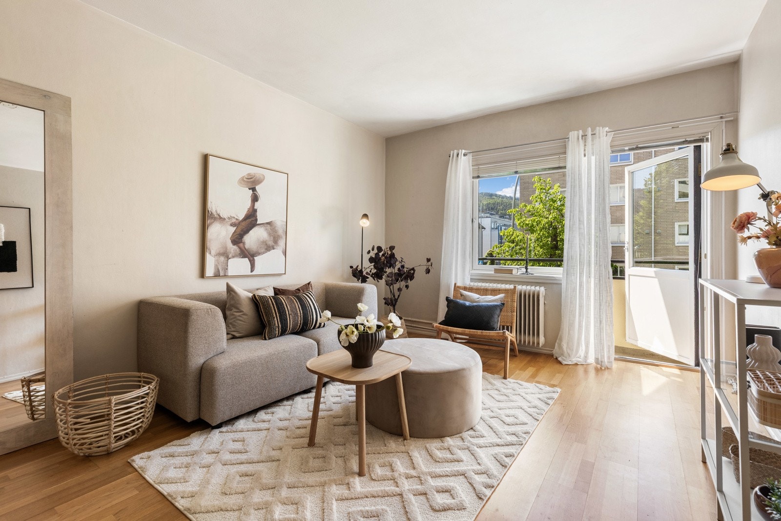 Lys stue med parkettgulv, store vinduer og utgang til balkong. Galleribilde