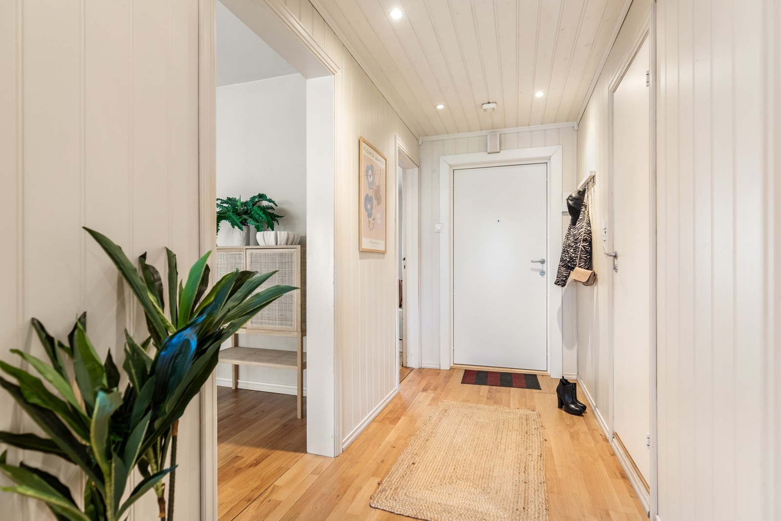 Lys gang med panelvegger, parkettgulv og downlights i taket. Galleribilde