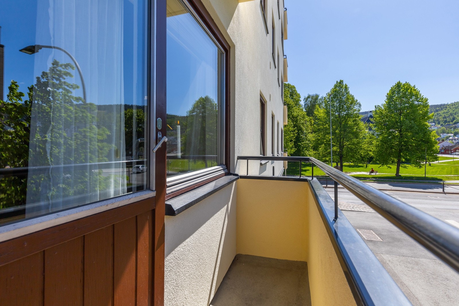 Liten balkong med utsikt mot grøntområde og vei. Galleribilde