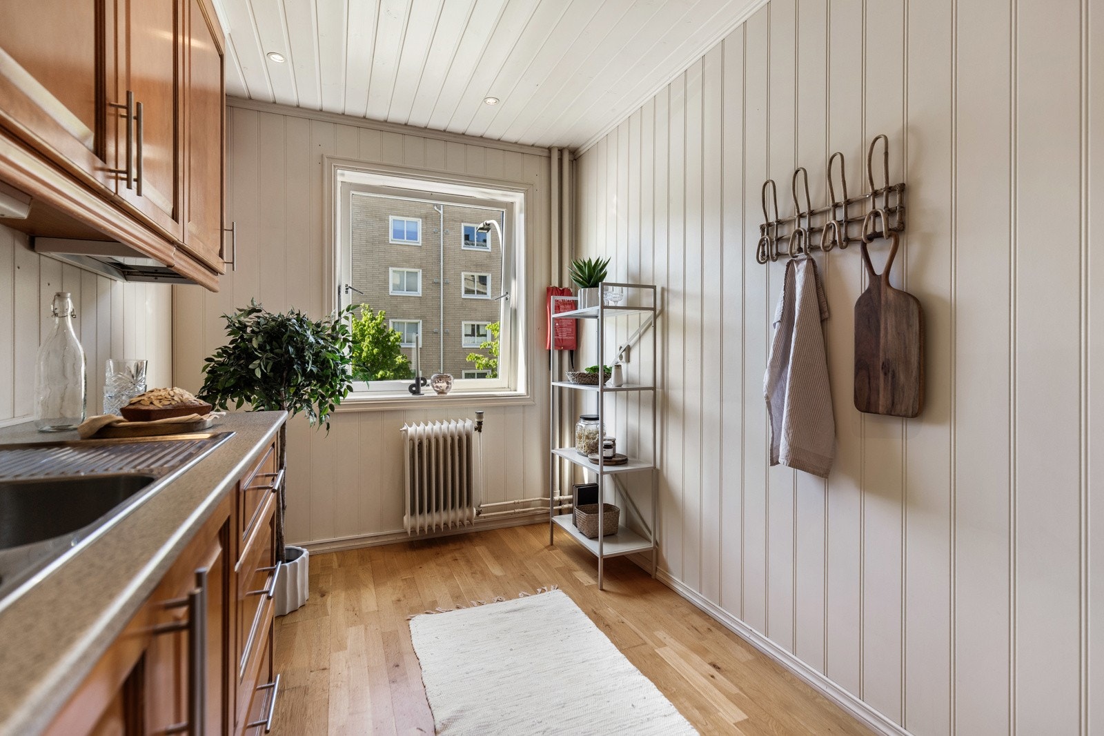 Lyst kjøkken med store vinduer, panel på veggene og parkettgulv. Galleribilde