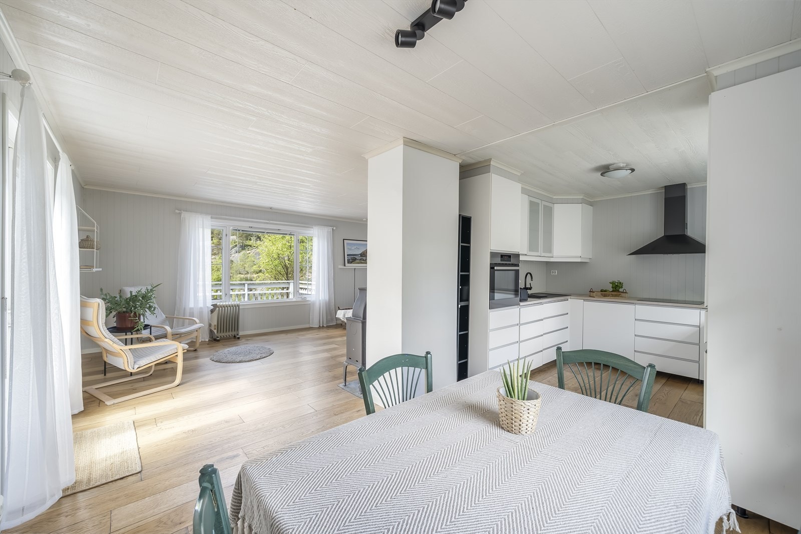 Lys stue med store vinduer som slipper inn naturlig lys. Moderne kjøkken med stilrent design. Galleribilde