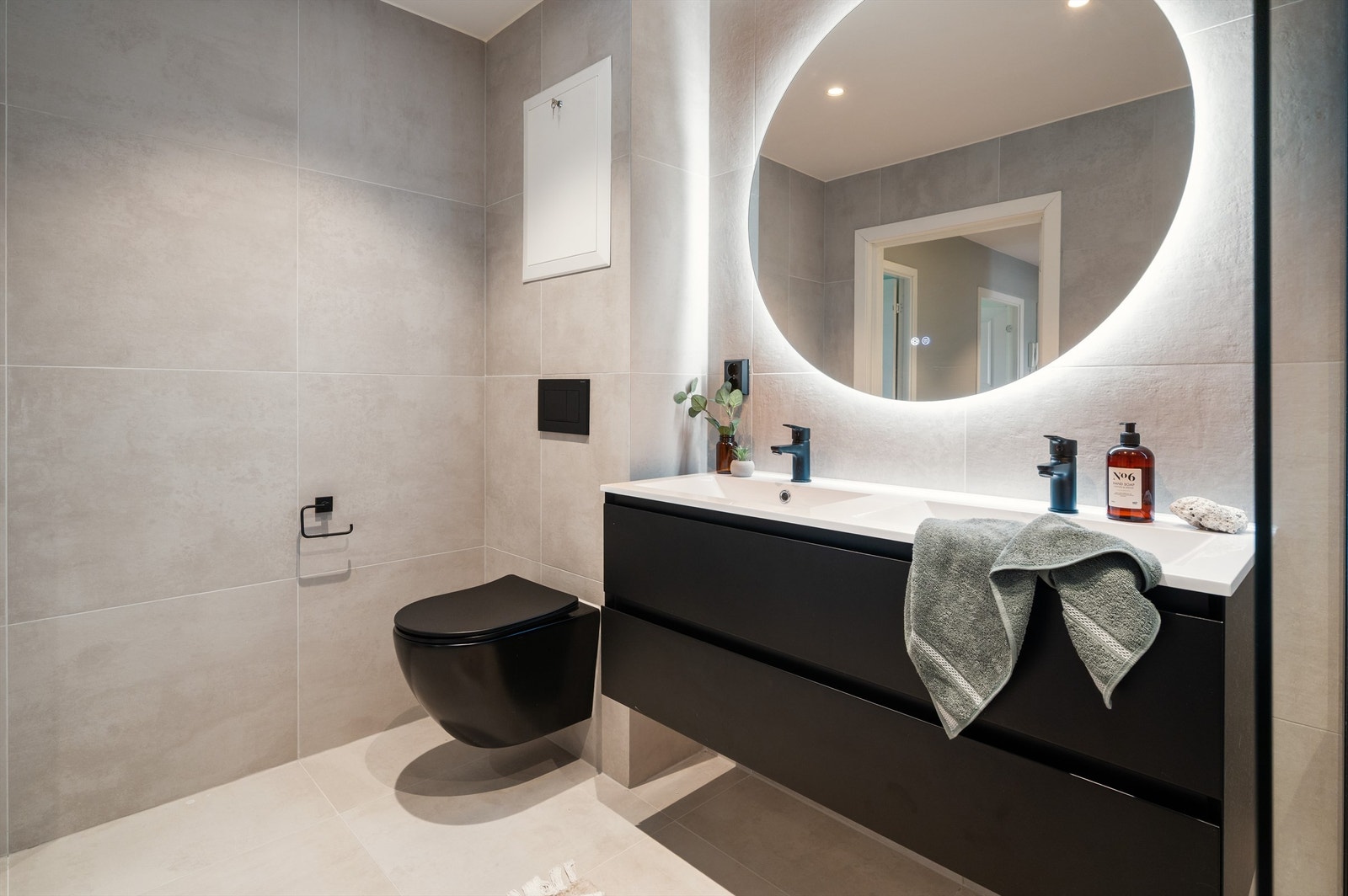 Badet er innredet med vegghengt klosett, servant med innredning, stort speil m/lys og dusjhjørne med glassvegg. Varmekabler i gulv. Galleribilde