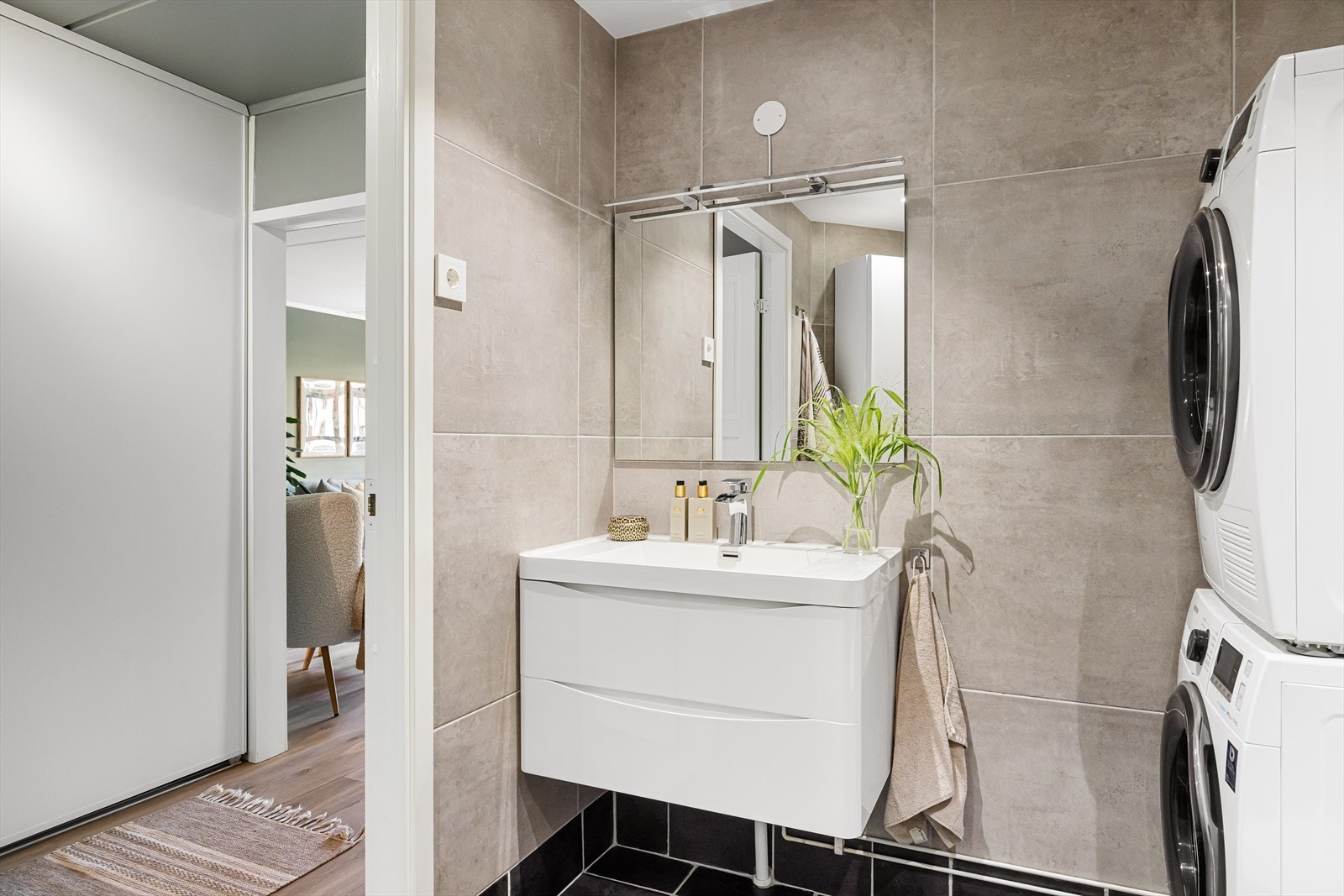 Badet er innredet med servantskap med glatte, høyglansede fronter og heldekkende servant, samt speil og veggmontert belysning. Galleribilde