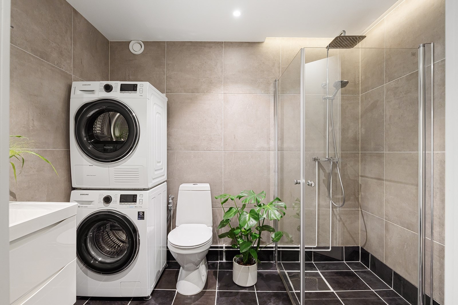 Delikat, flislagt baderom med gulvvarme og downlights i himlingen. Praktisk opplegg for vaskemaskin. Galleribilde