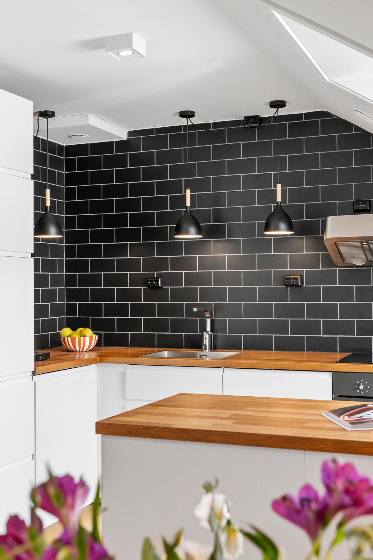 Innredning med hvite glatte, folierte fronter. Benkeplate i heltre eik, med nedfelt kum i rustfritt stål. Fliser på vegg over benk Galleribilde