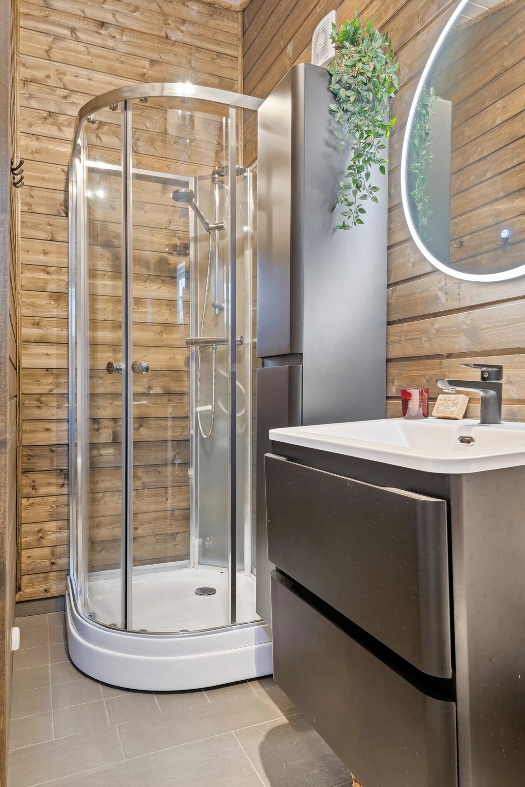 Badet er innredet med toalett, dusjkabinett, opplegg for vaskemaskin, og servant med innredning. Galleribilde