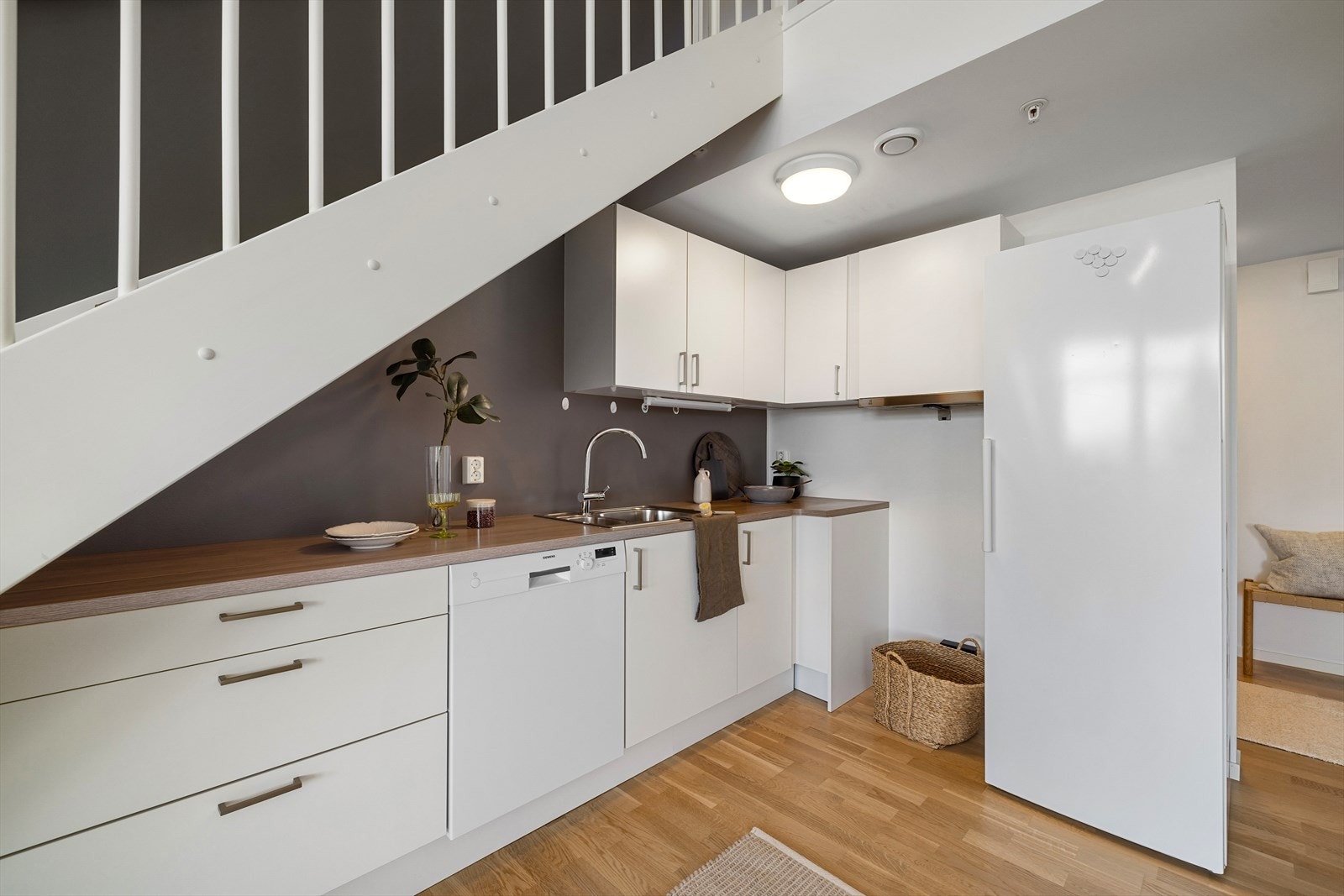 Kjøkken har åpen løsning mot stuen og har innredning fra Norema med slette, hvite fronter og benkeplate av laminat. Galleribilde
