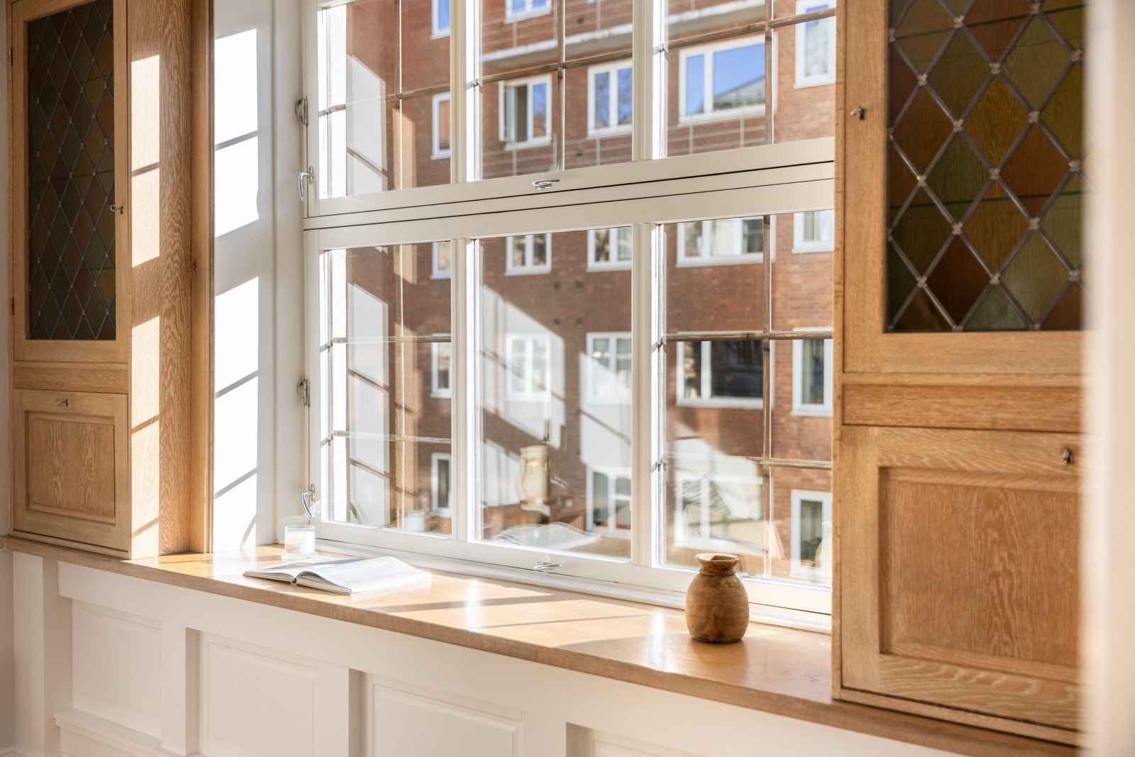 Stort vindu med dyp vinduskarm og nydelige vetrineskap på hver side i eik. Galleribilde