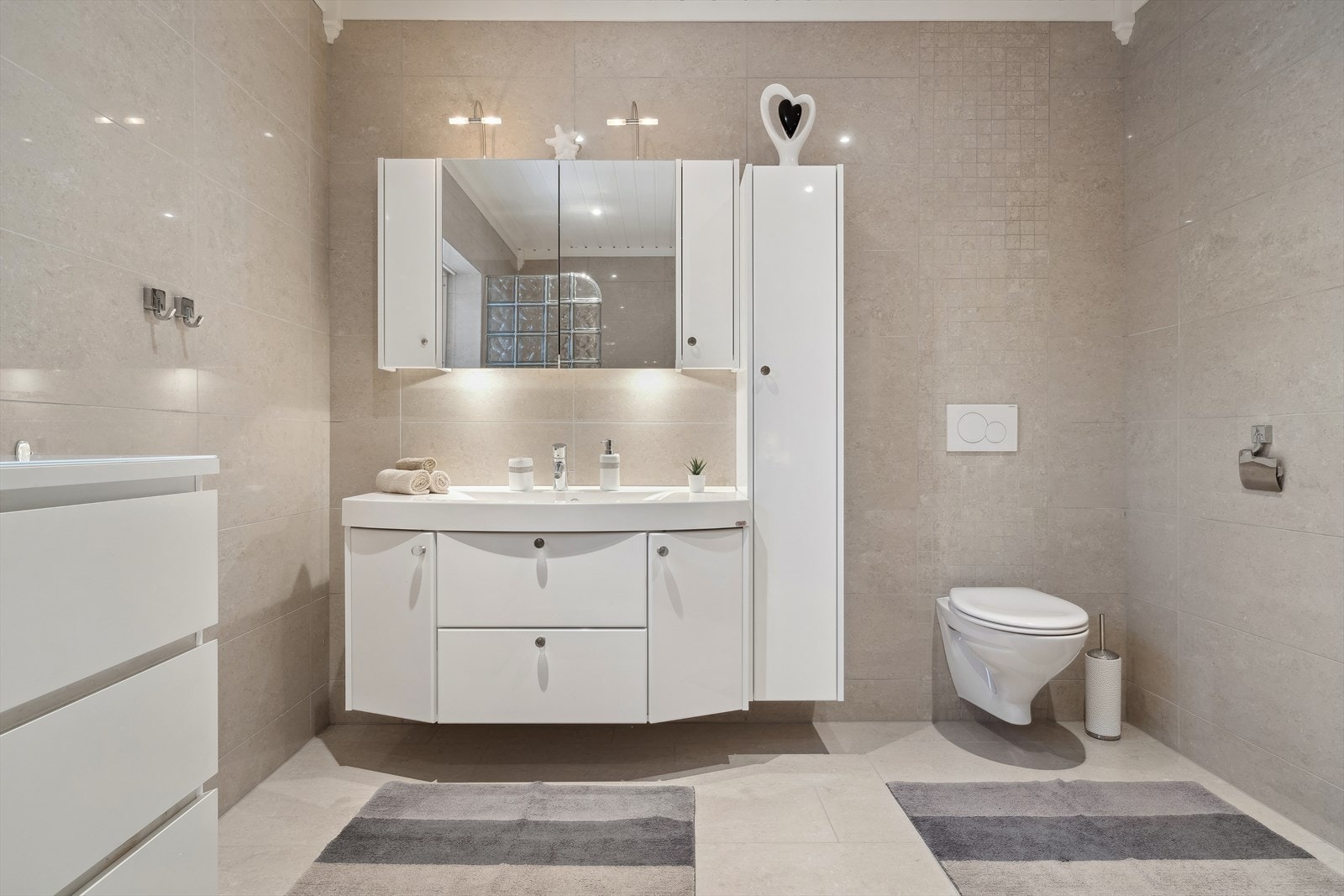 Badet har tidløse og behagelige farger på flis og baderomsinnredning. Galleribilde