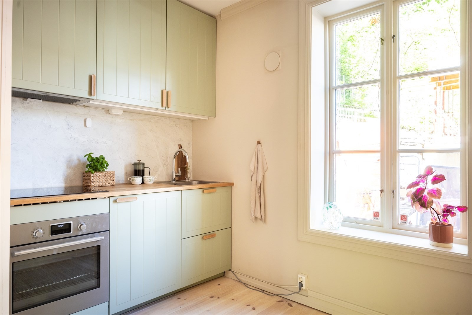 Stilrent og flott kjøkken fra 2024 bestående av grønne profilerte fronter og benkeplate av heltre med nedfelt vaskekum. Galleribilde