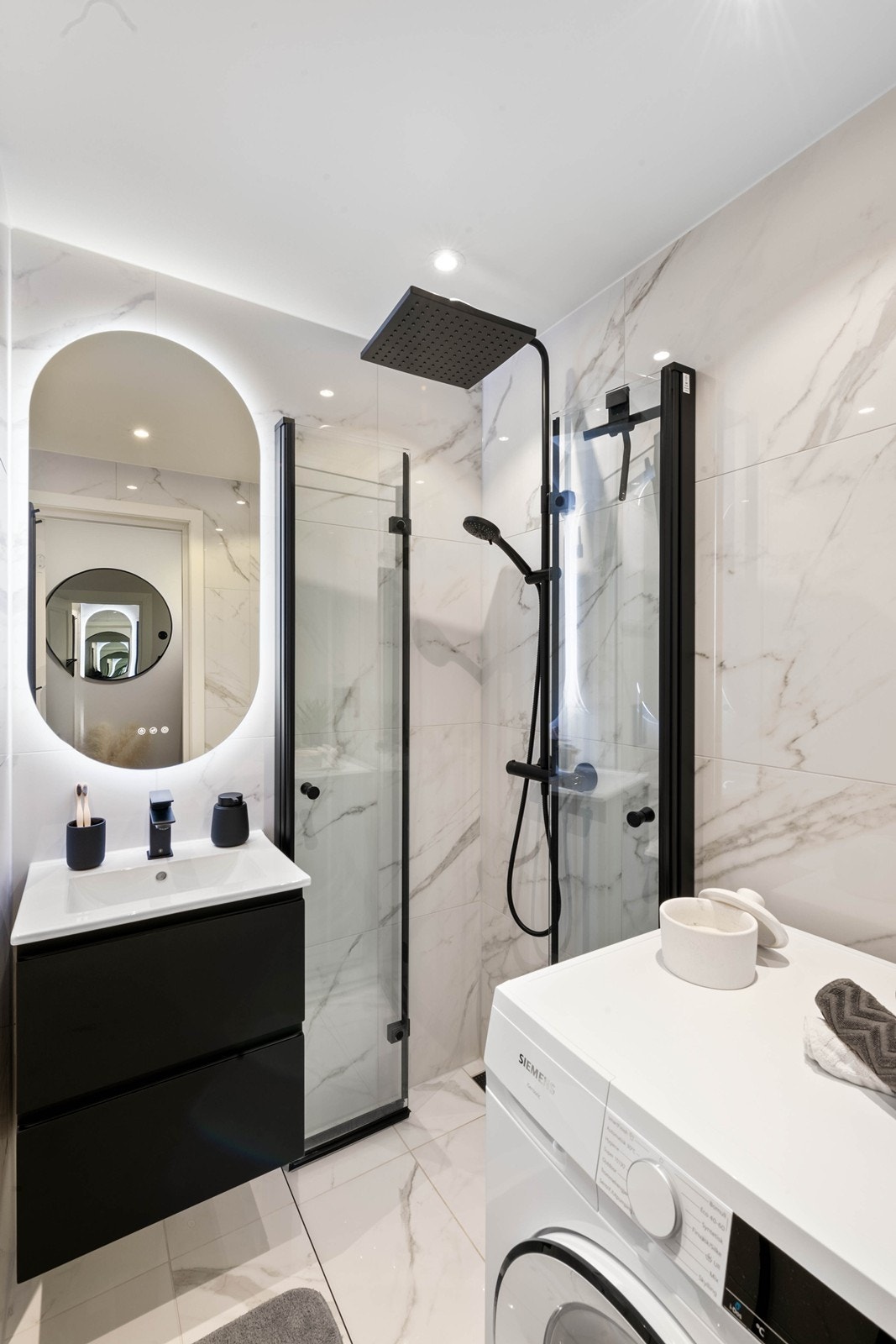 Lekkert og påkostet bad med marmorfliser og opplegg for vaskemaskin Galleribilde