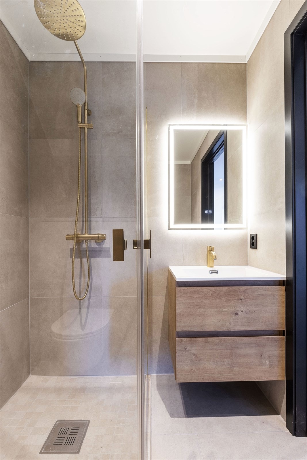 Badet i 1. etasje er helfliset med dusjhjørne - i tillegg er det montert toalett og servantseksjon Galleribilde