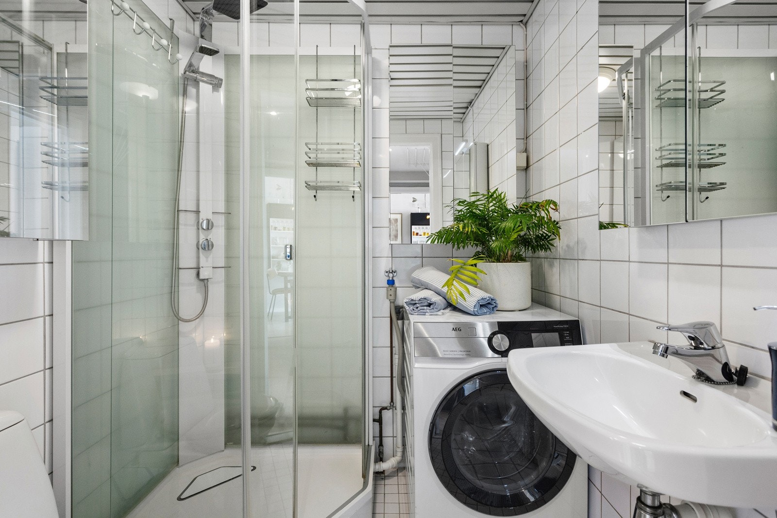 Flislagt bad med gulvvarme, innredet med servant, gulvstående toalett, dusjkabinett og opplegg for vaskemaskin Galleribilde