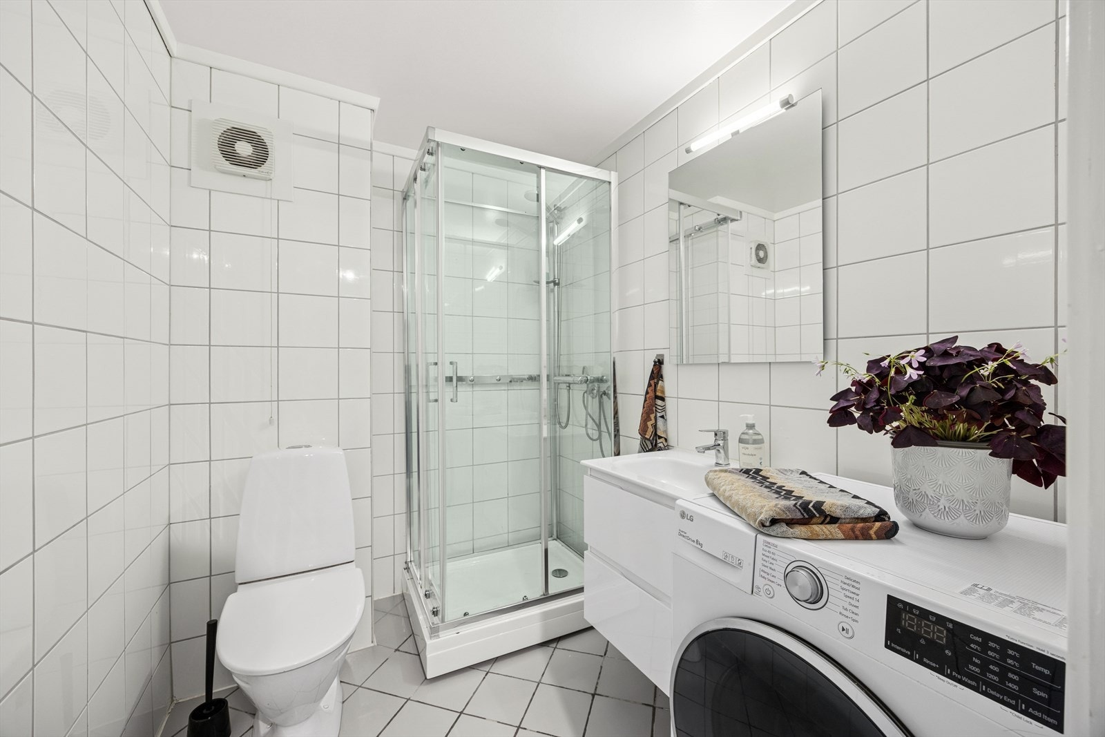 Lekkert, flislagt baderom fra 2002 som oppleves både tidløst, praktisk og romslig. Her finner du servant med underskap fra 2022, speil med integrert belysning, toalett og dusjløsning fra samme år. Galleribilde