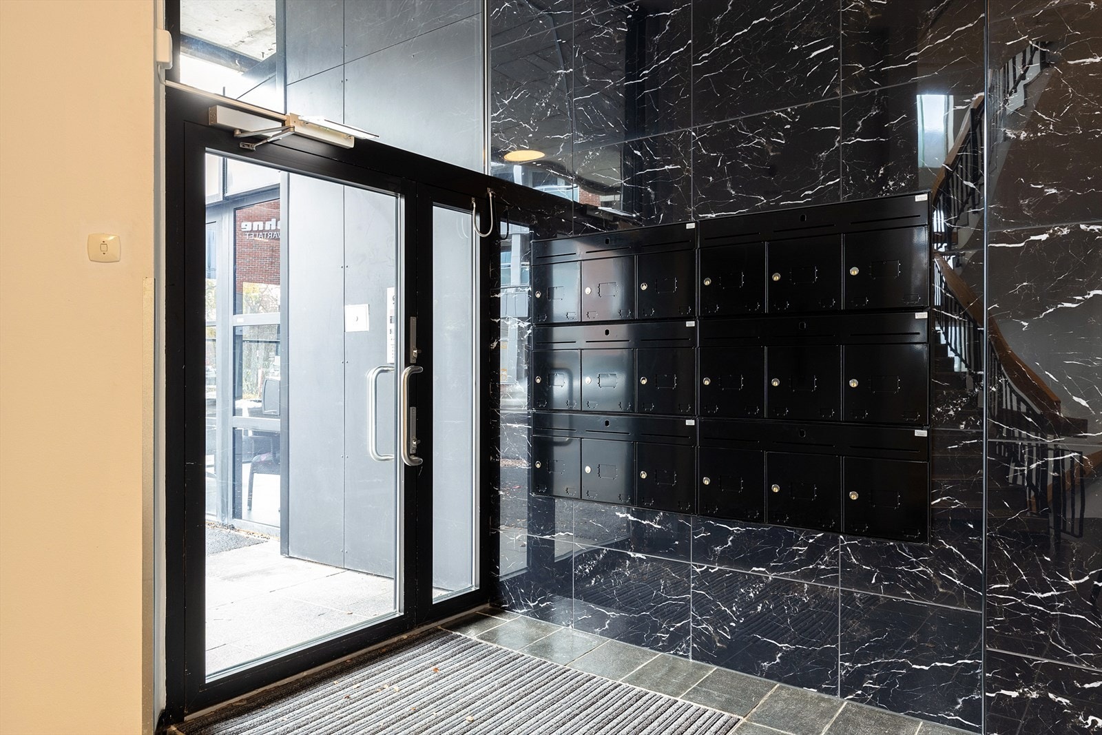 Felles inngangsparti med postkassevegg og heis opp til etasjene. Hver etasje har adkomst til felles veranda fra gangen. Galleribilde