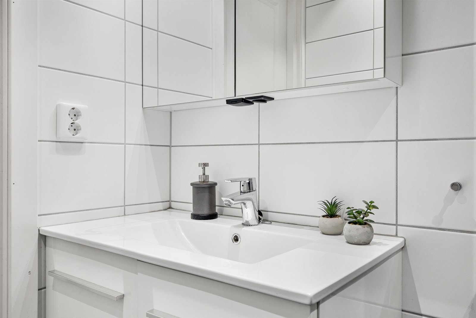 Badet har mørke gulvfliser med varmekabler under, hvite veggfliser og downlights i tak Galleribilde