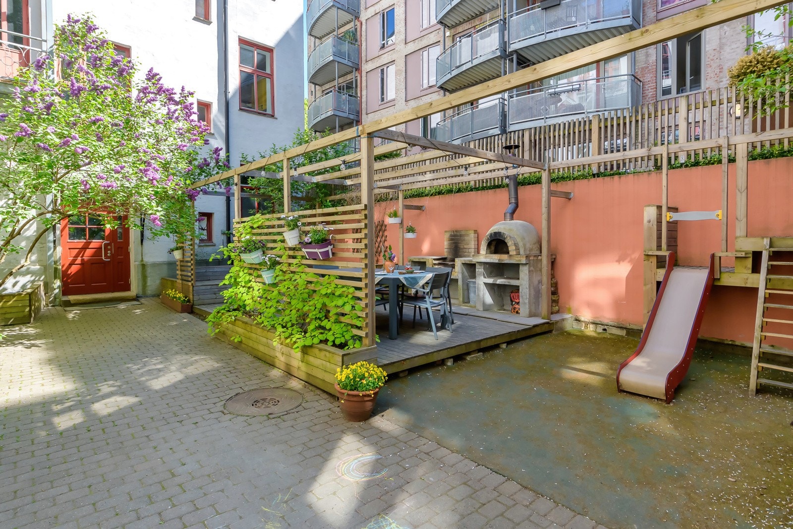 Nydelig bakgård med utekjøkken, pizzaovn og sitteplasser i grønne omgivelser. Galleribilde