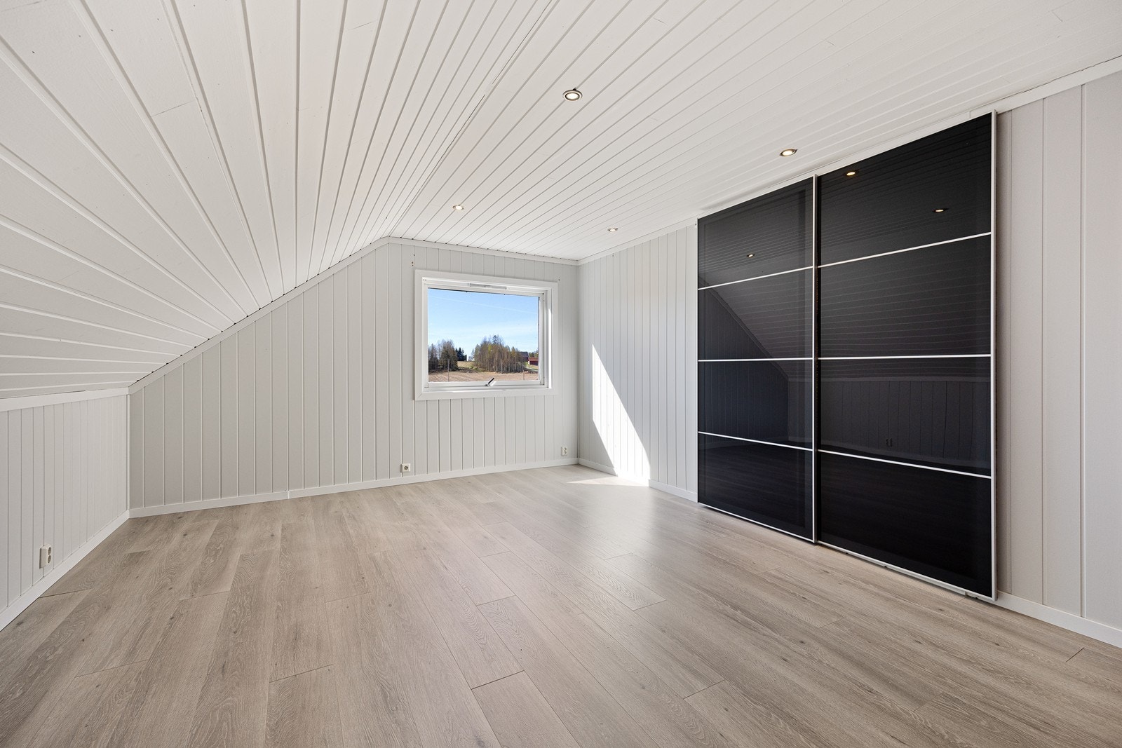 Hovedsoverommet har downlights og sorte skyvedører i glass inn til et romslig garderoberom. Galleribilde