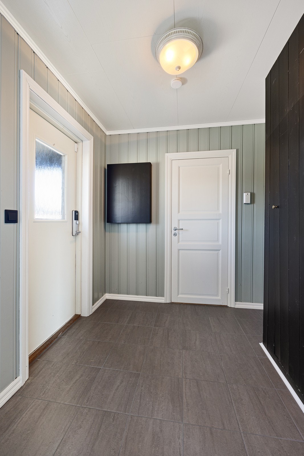 Entreen fremstår innbydende med fliser på gulvet og god oppbevaringsplass i mørke garderobeskap. Galleribilde