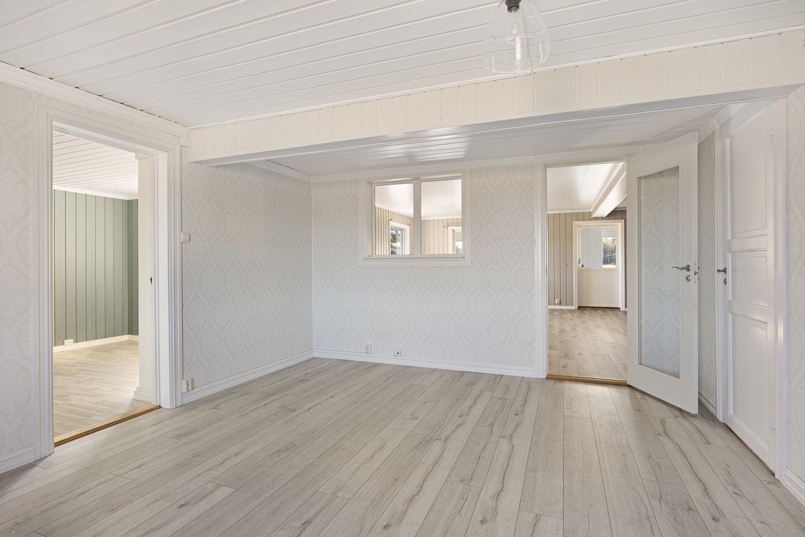 Tv-stuen har vindu mot hovedstuen, hvitmalt panelhimling og delikat, lys mønstertapet på veggene. Galleribilde