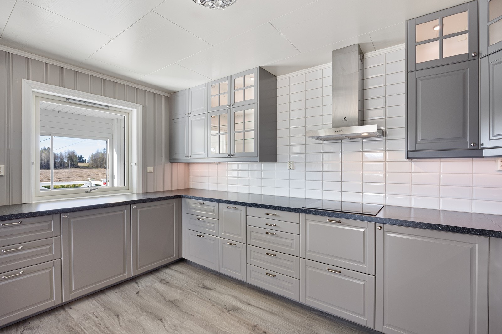 Kjøkkenet er utstyrt med integrert stekeovn og platetopp, samt ventilator og hvite metrofliser over benken. Galleribilde