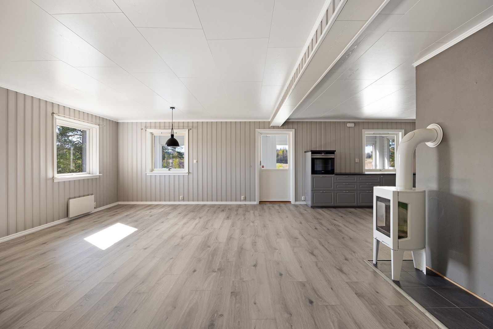 Stuen er stor og luftig med åpen løsning til kjøkkenet og hygge fra en peisovn. Galleribilde