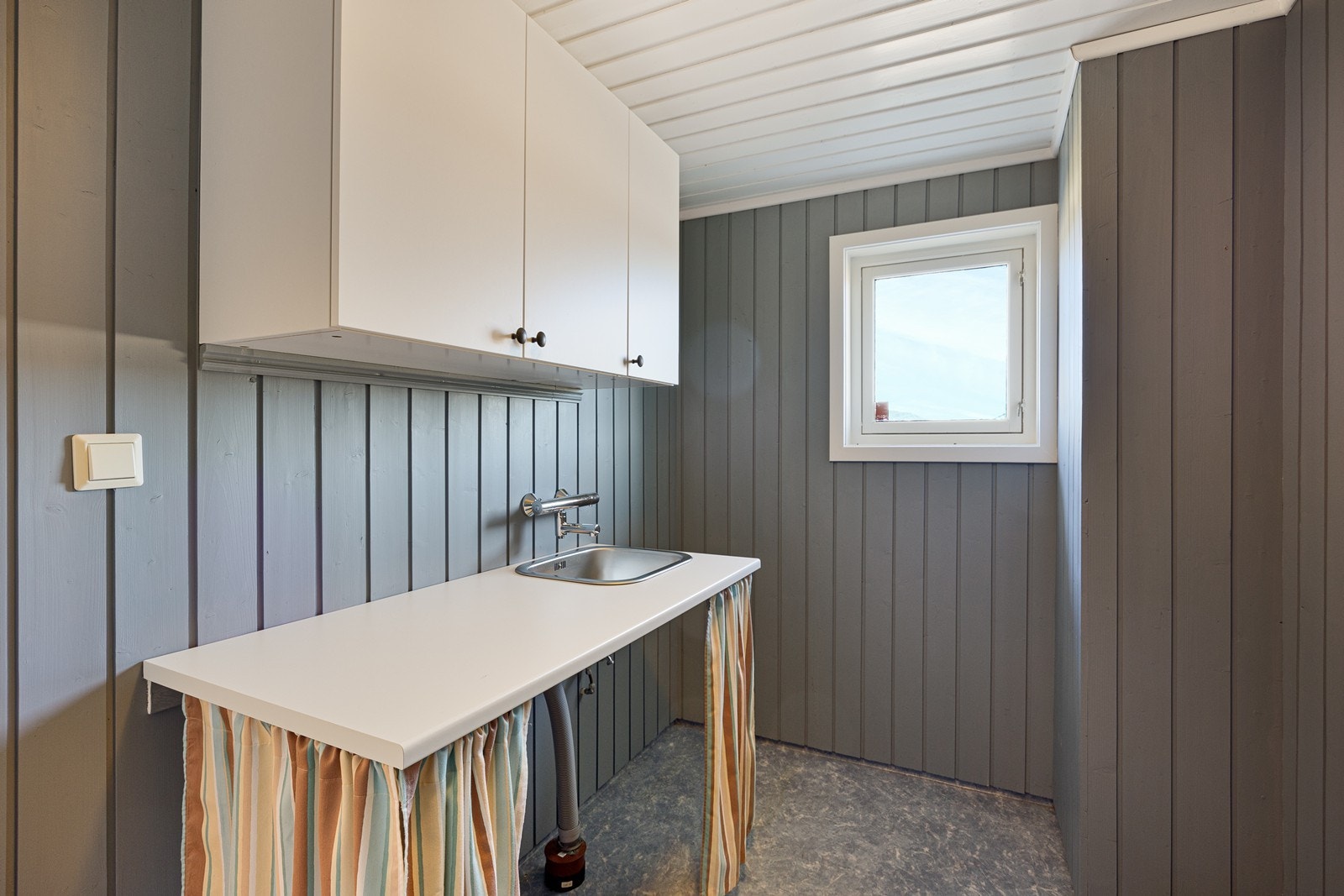 Vaskerommet ligger tilknyttet badet og er innredet med vaskekum, benk og veggskap, samt opplegg for vaskemaskin. Galleribilde