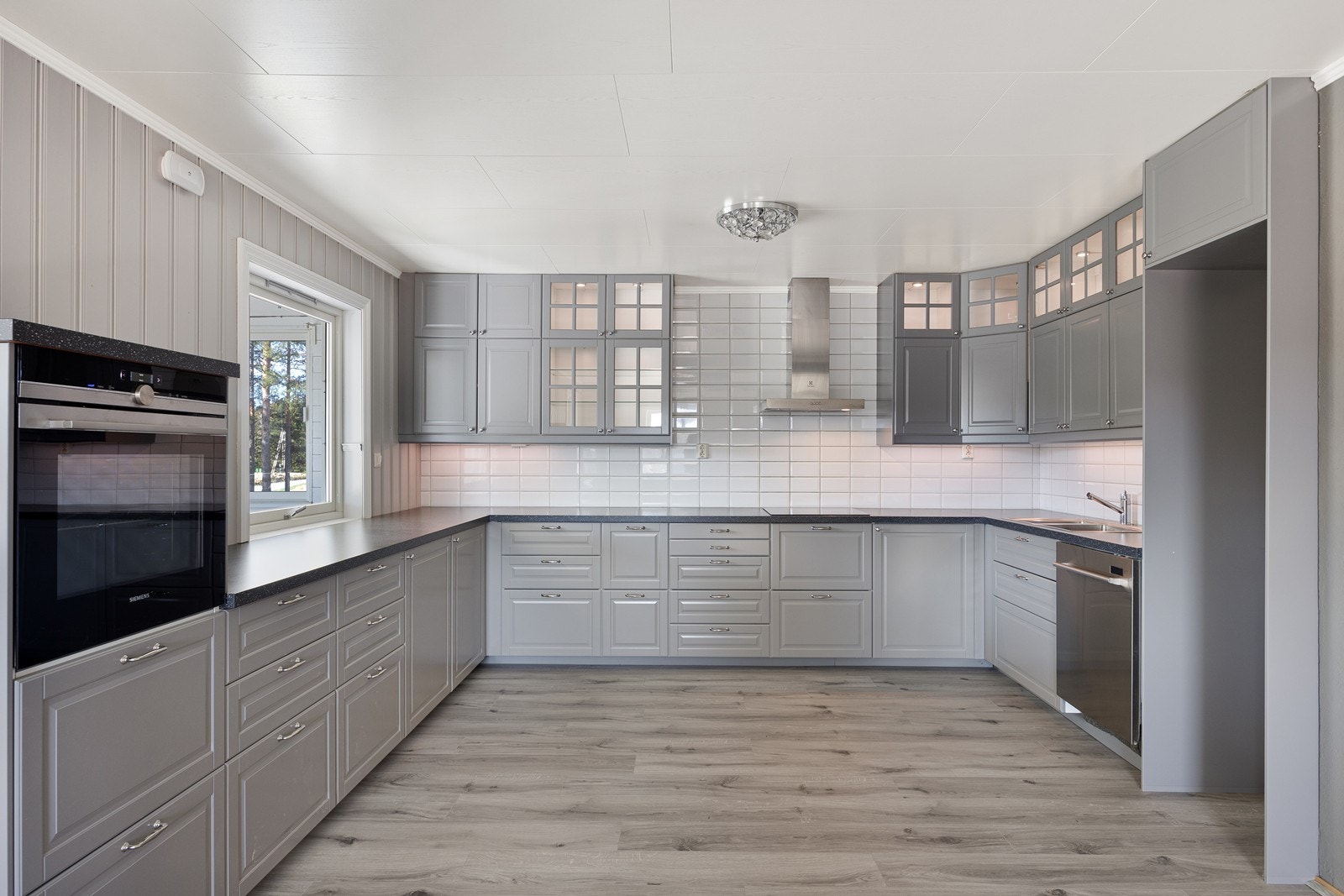 Kjøkkenet fikk ny innredning i 2016, i klassisk stil med har grå, profilerte fronter og mørk benkeplate i laminat. Galleribilde