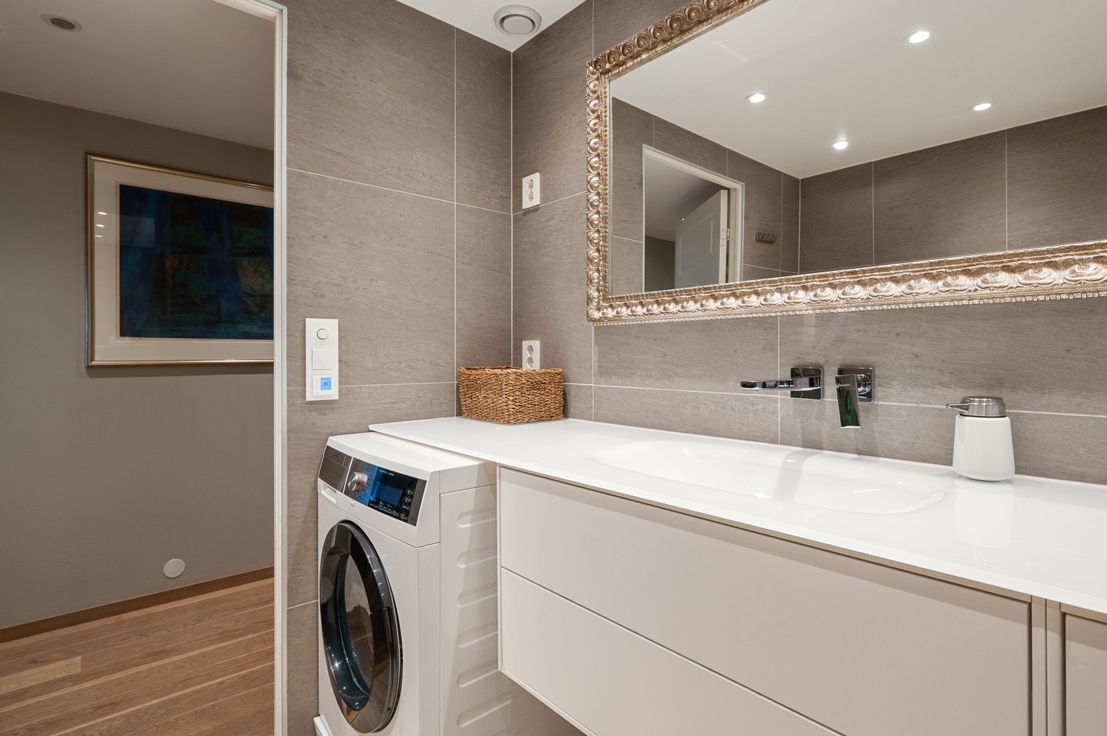 Moderne bad med stor speilramme, integrert vaskemaskin og stilrent servantskap. Galleribilde