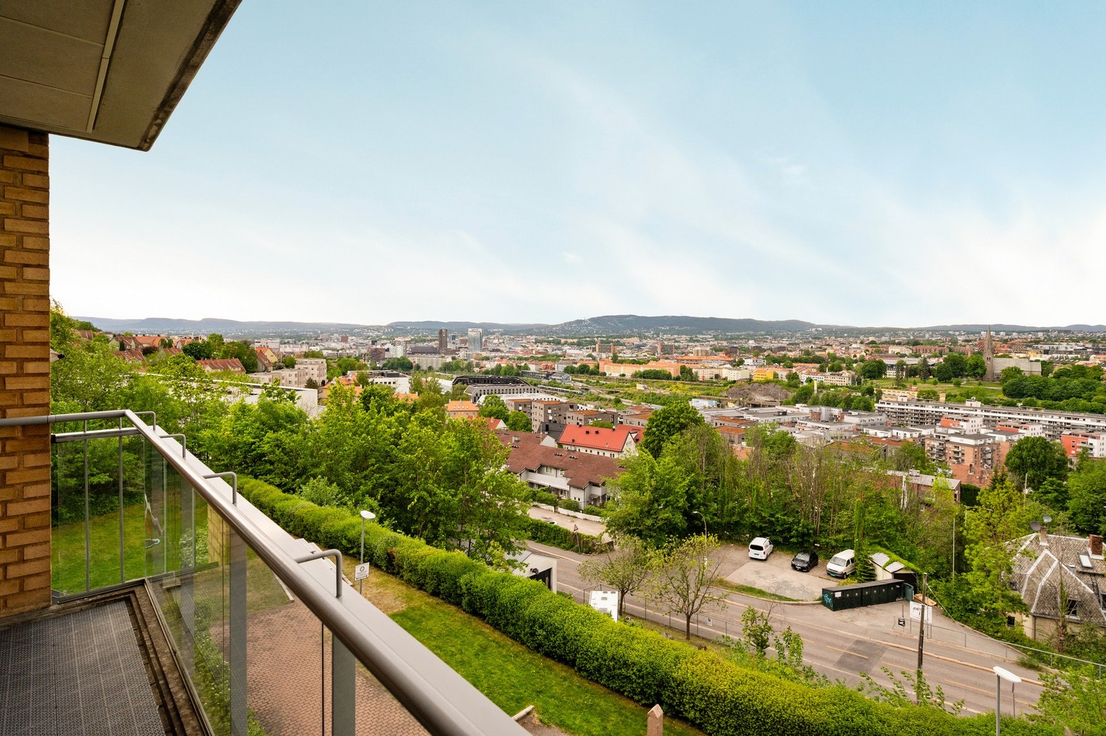 Utsikt over byen med grønne områder, bygninger og fjell i bakgrunnen. Galleribilde