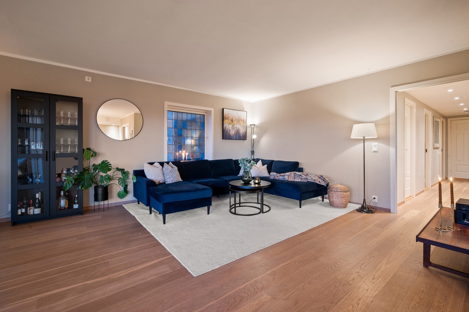 Åpen stue med parkettgulv, sofa, spisebord og store vinduer som gir godt lysinnslipp. Galleribilde