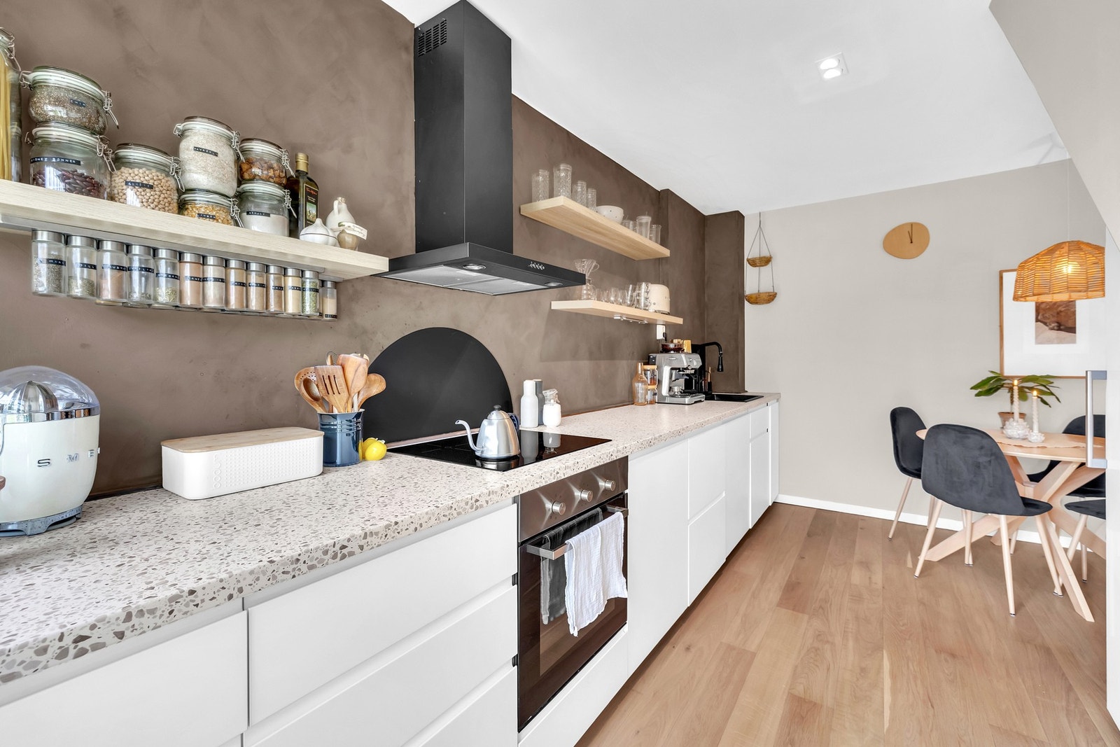 Velorganisert kjøkken med gjennomtenkt oppbevaring og helhetlige materialvalg. Detaljer som krydderhylle og vegghengt ventilator gir både funksjon og stil. Galleribilde