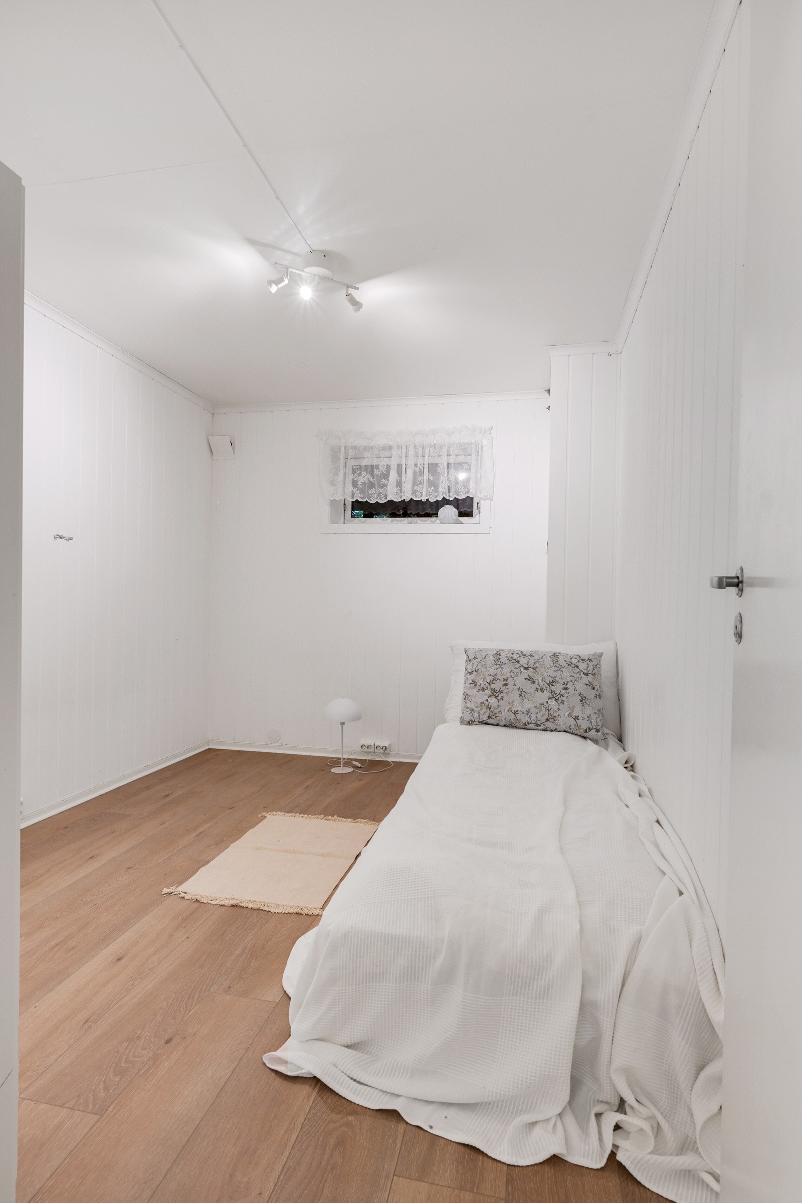 Lys og pen sovealkove med laminat på gulv og slette plater på vegger Galleribilde