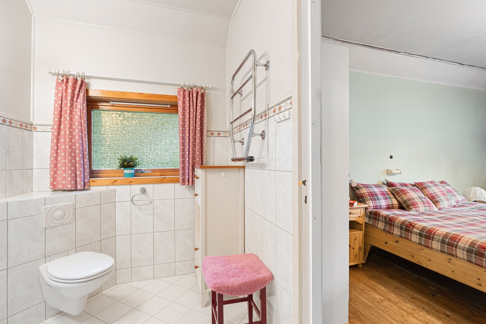 Badet inneholder vegghengt toalett og servant, speil over servant og håndkletørker på vegg. Galleribilde