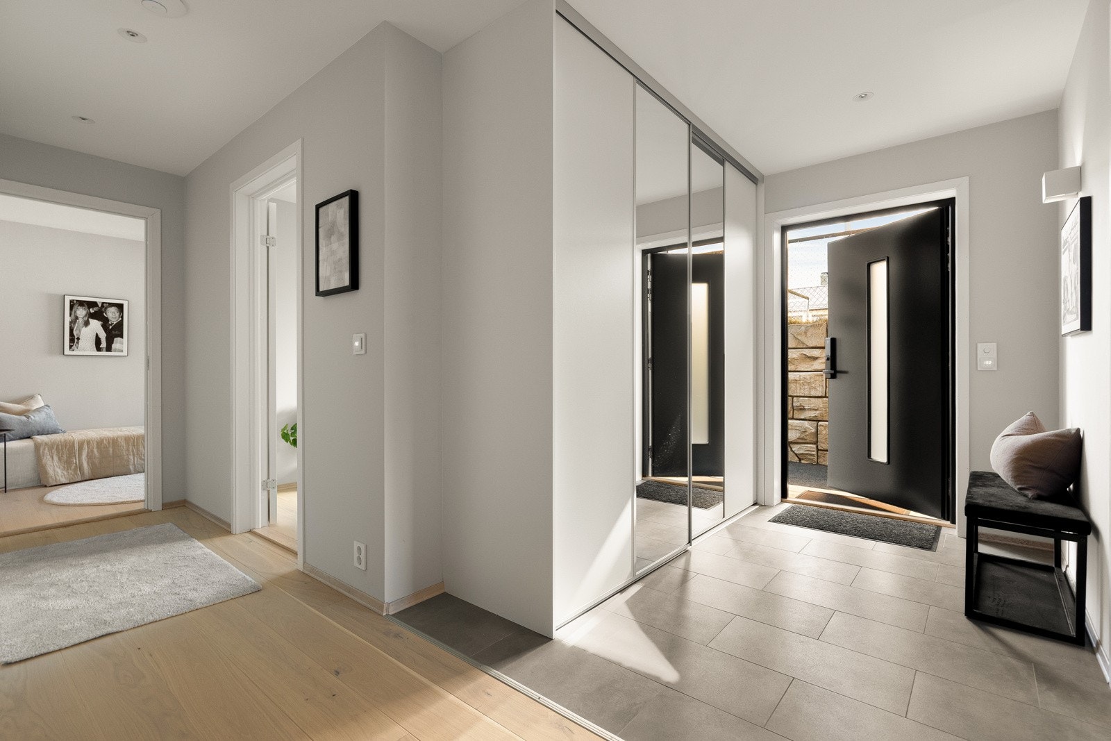 Innbydende entré med fliser som gir et praktisk og stilrent førsteinntrykk. Downlights i taket skaper et godt og behagelig lys, og den moderne hoveddøren er utstyrt med ID lock som er tilkoblet smarthus. Galleribilde