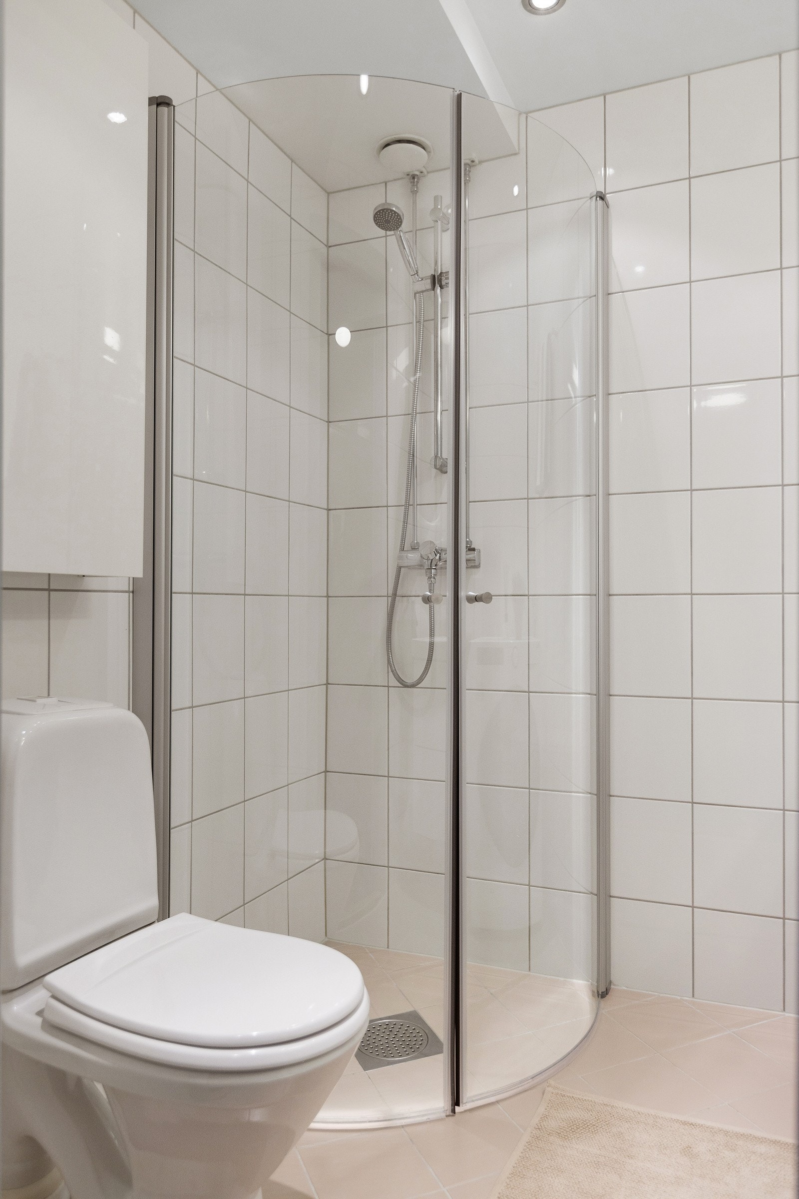 Dusjhjørne med innfellbare dusjvegger, toalett og servant med ettgreps blandebatteri i innredning. Galleribilde