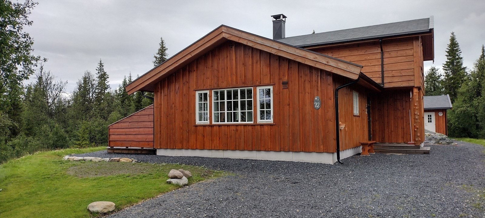 Adkomst fra helårsvei, gruset innkjørsel og opparbeidet parkering på tomt utenfor hytte. Galleribilde