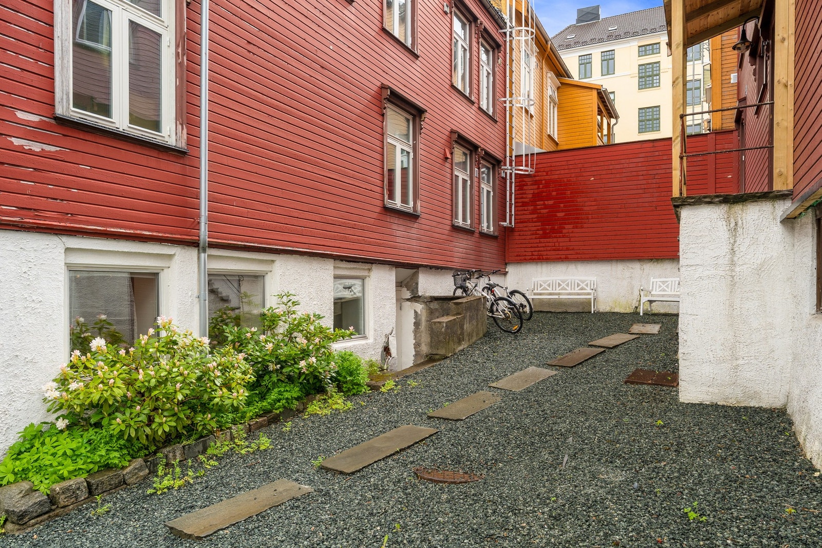Felles bakgård med gruslagt plass, beplantning og sittebenker. Galleribilde